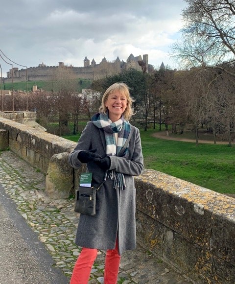 Kate Mosse standing on a bridge with the walls of Carcassonne behind her