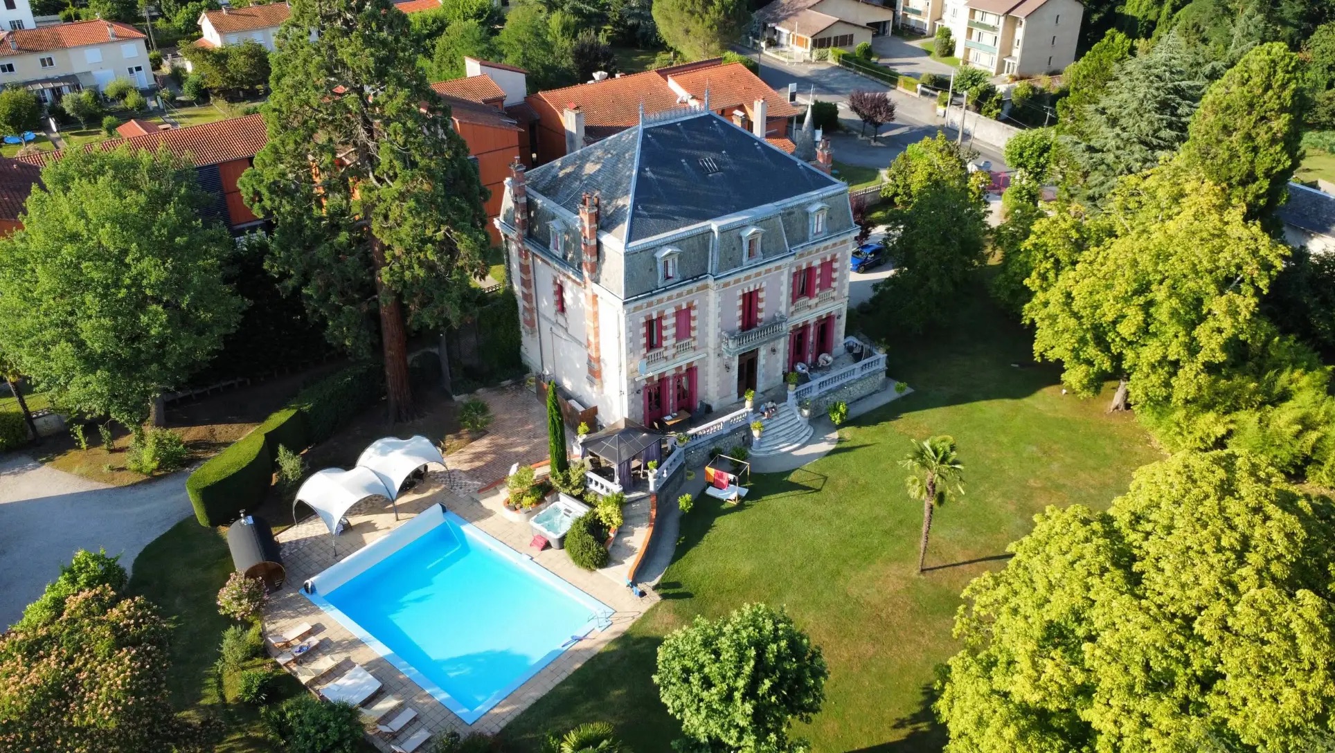 Aerial view of the château, its swimming pool, hot tub, sauna and lawns surrounded by mature trees