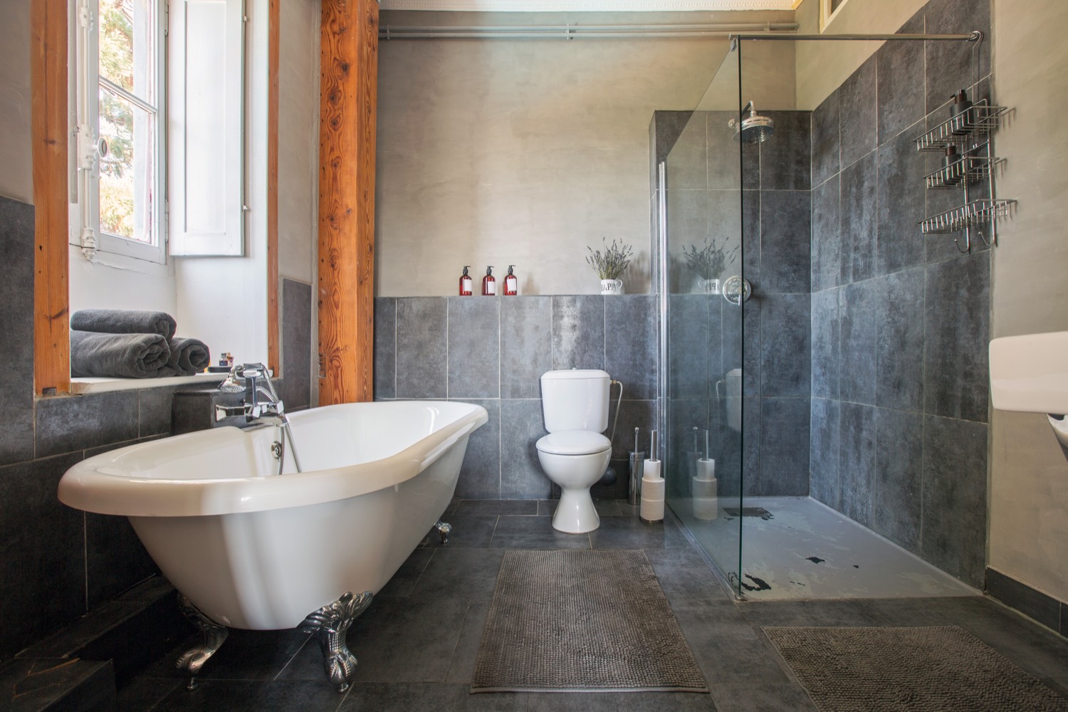 Bathroom with a roll-top bath, slate tiles and a glass walk-in shower