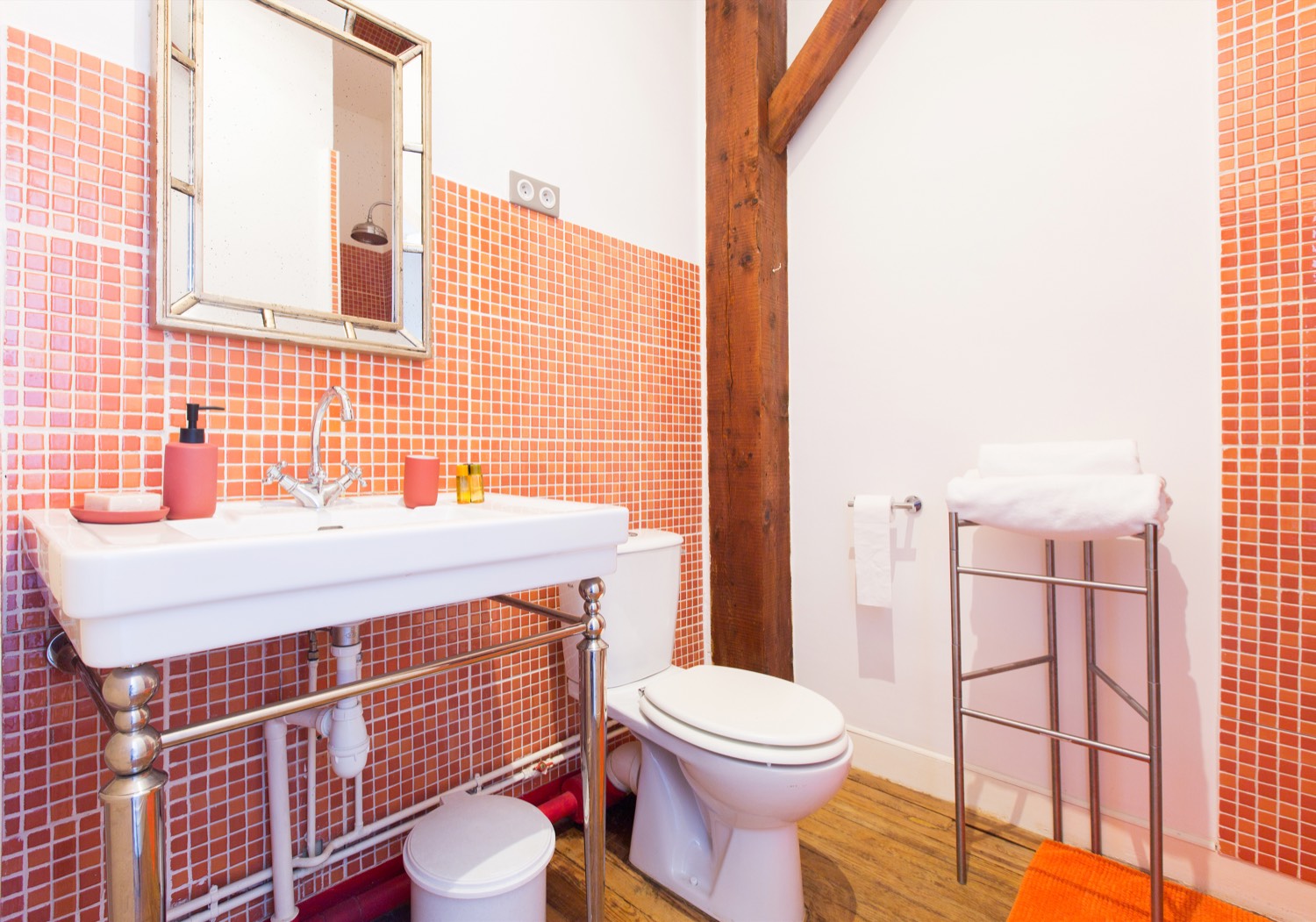 Bathroom with coral mosaic tiles, a washstand and an exposed wooden beam