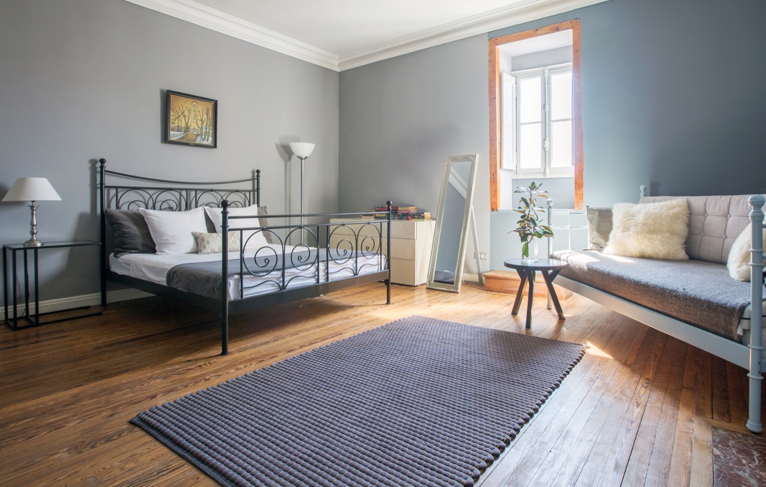 Blue bedroom with an iron bed, a day bed and a tall window