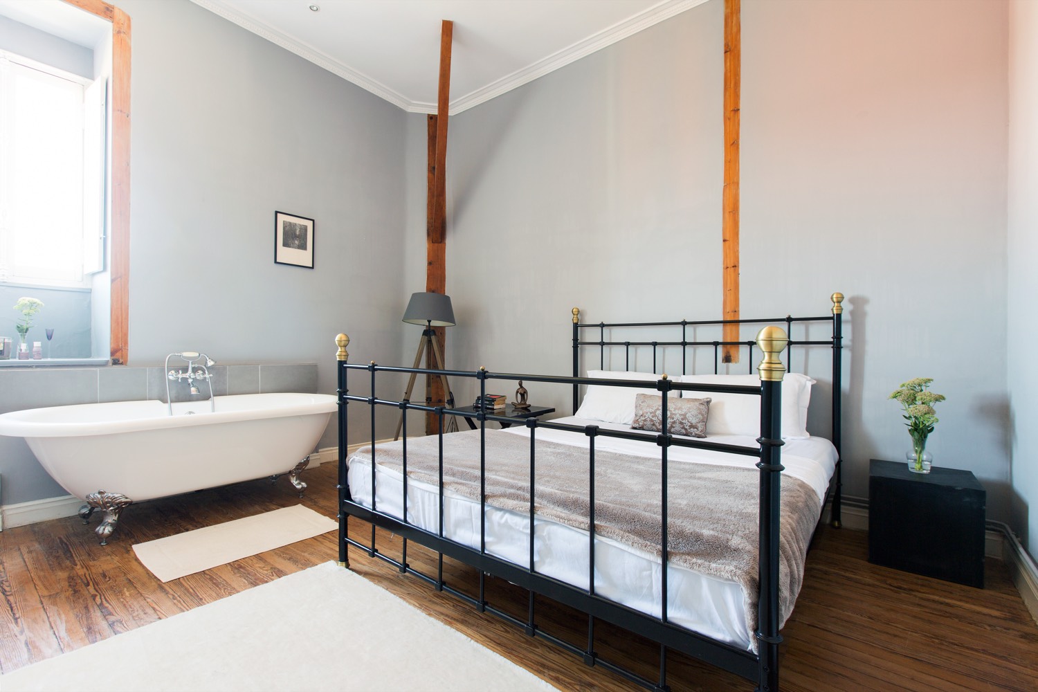 Bedroom with a brass and iron bed and a roll-top bath under the window