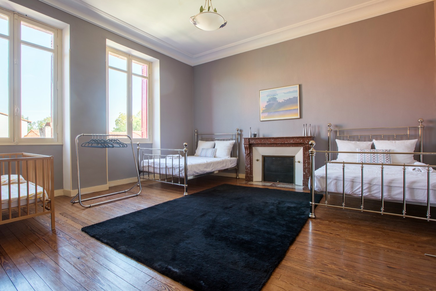 Large bedroom with three beds, a cot and a fireplace